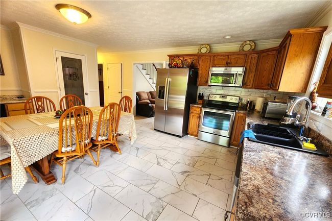Kitchen with appliances with stainless steel finishes, light marble finish floors, crown molding, tasteful backsplash, and a textured ceiling | Image 10
