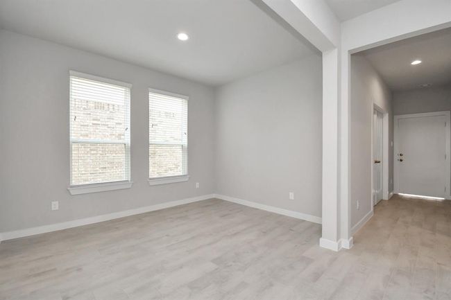An inviting dining space seamlessly woven into the open concept, connecting the family room and kitchen. Revel in the stunning floors, soothing paint palette, and the crowning touch of bright recessed lighting – a perfect setting for shared meals and cherished moments. | Image 12