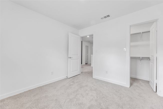 Unfurnished bedroom with a walk in closet, carpet flooring, visible vents, and baseboards | Image 17