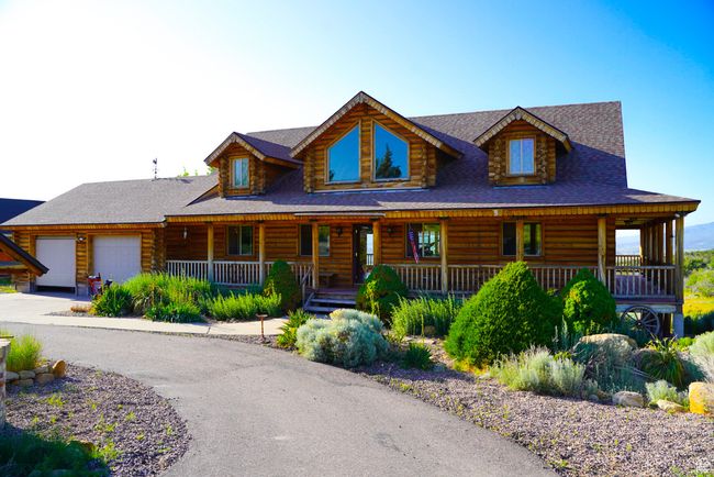 Log home featuring log exterior, a garage, covered porch, and driveway | Image 6