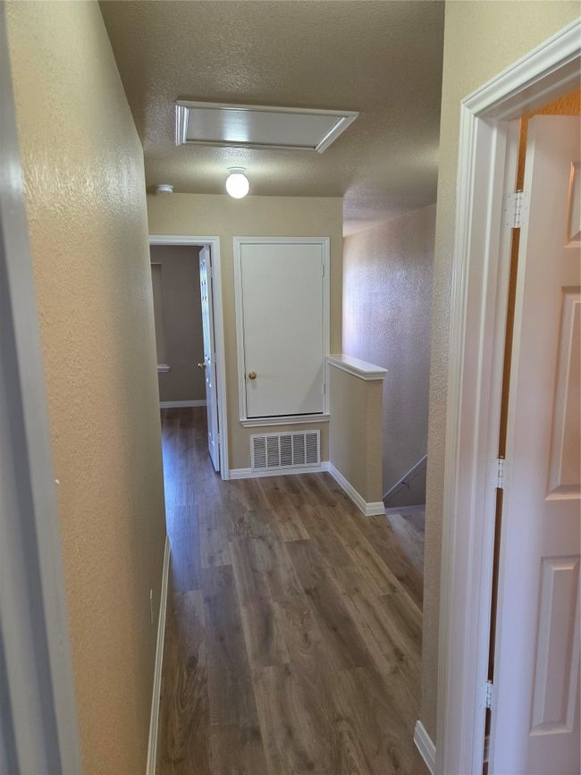 Hallway featuring attic access, wood finished floors, a textured wall, an upstairs landing, and a textured ceiling | Image 18