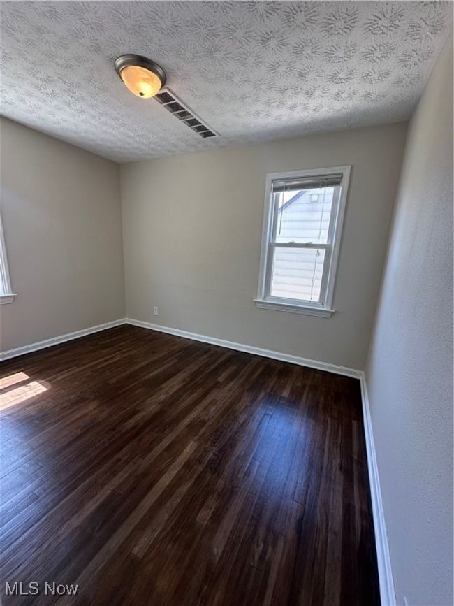 Empty room with baseboards, visible vents, a textured ceiling, and dark wood-style flooring | Image 20