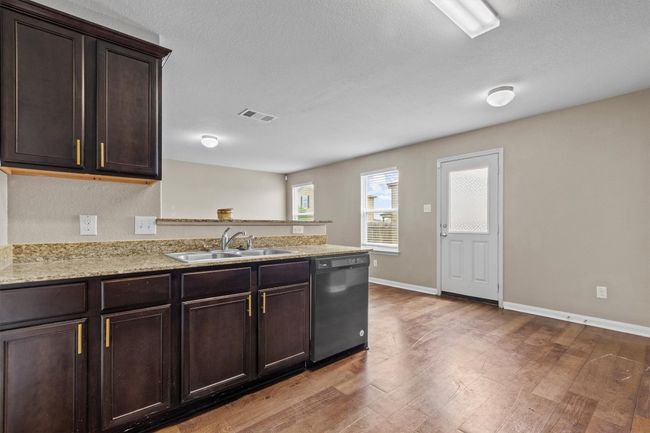 Kitchen featuring dark brown cabinetry, a sink, dishwasher, a peninsula, and wood finished floors | Image 8