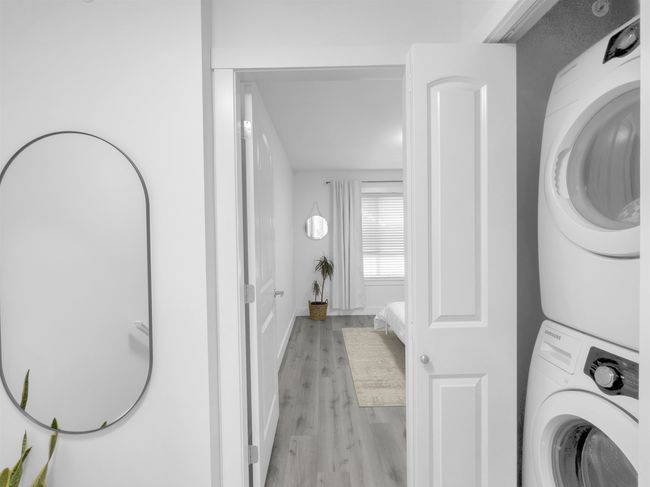 Clothes washing area featuring laundry area, stacked washer and dryer, baseboards, and light wood finished floors | Image 23
