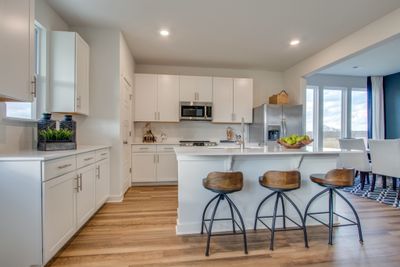 This kitchen is a dream come true with its quartz counter tops, under mount sink, and 42" shaker cabinets! Photo is of Welcome Home Center in another community. Finishes may vary. | Image 3