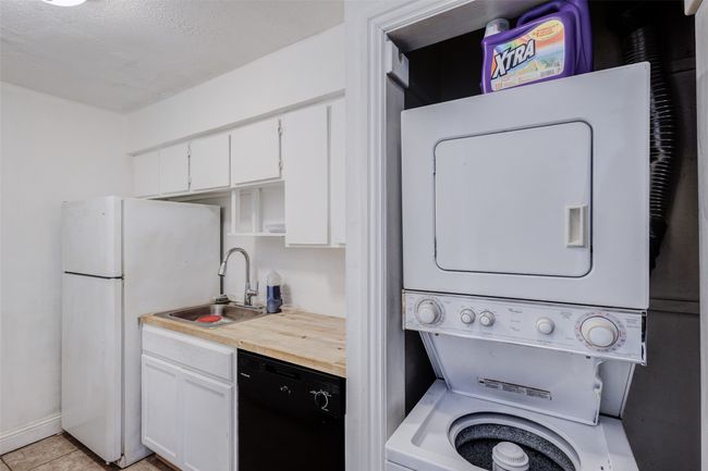 Washroom featuring light tile patterned floors, stacked washer / dryer, laundry area, and a sink | Image 6