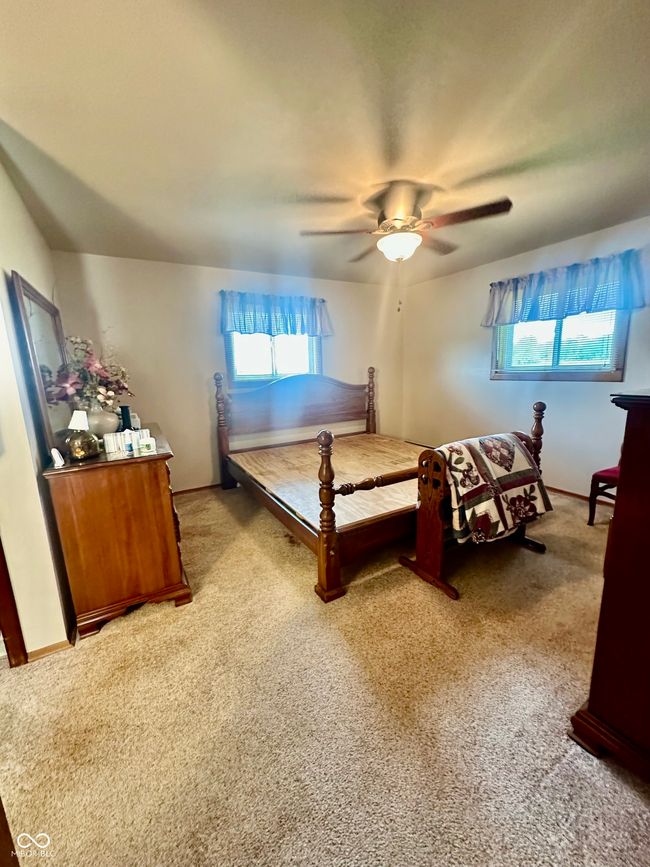 bedroom with light colored carpet, ceiling fan, and baseboards | Image 23