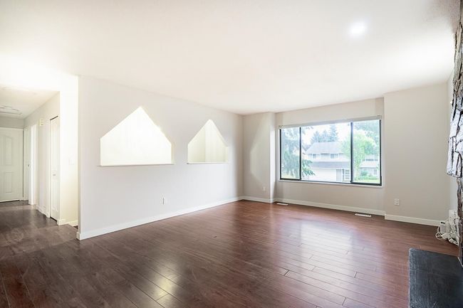 Unfurnished living room featuring dark wood-type flooring and baseboards | Image 5