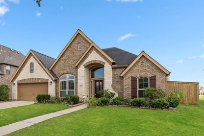 Upon arrival to this STUNNING home, elegance greets you prior to entry with a welcoming walkway to the arched door way, beautiful brick and stone elevation and abundance of greenspace. | Image 2