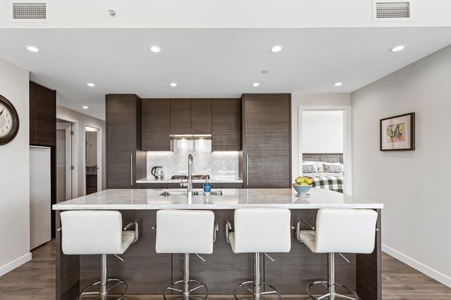 Kitchen featuring modern cabinets, dark brown cabinetry, a kitchen island with sink, and visible vents | Image 5