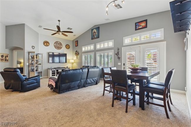 Dining space featuring visible vents, a ceiling fan, light colored carpet, arched walkways, and high vaulted ceiling | Image 12
