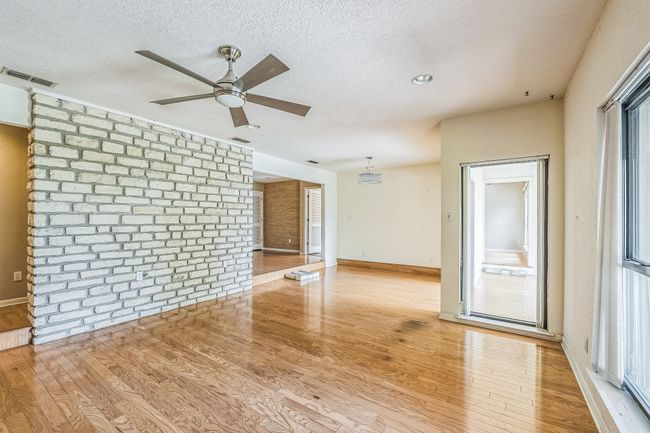 Unfurnished living room with a ceiling fan, visible vents, baseboards, a textured ceiling, and wood finished floors | Image 29