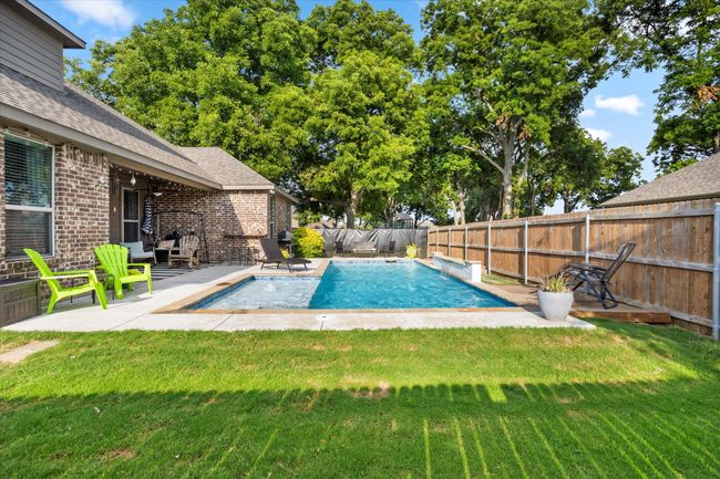View of swimming pool featuring a fenced backyard, a lawn, and a patio | Image 30