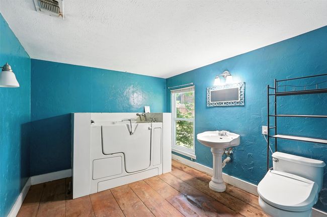 Full bathroom with a textured ceiling, hardwood / wood-style floors, a garden tub, and a textured wall | Image 27