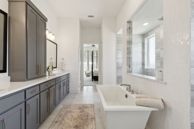 Ensuite bathroom with a ceiling fan, tile patterned floors, double vanity, a freestanding bath, and baseboards | Image 18