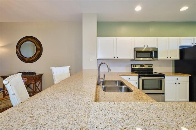 Kitchen featuring light stone countertops, white cabinetry, a sink, and appliances with stainless steel finishes | Image 16
