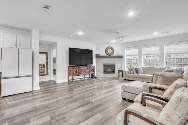 Living room featuring ceiling fan, a fireplace, and light hardwood / wood-style flooring | Image 7
