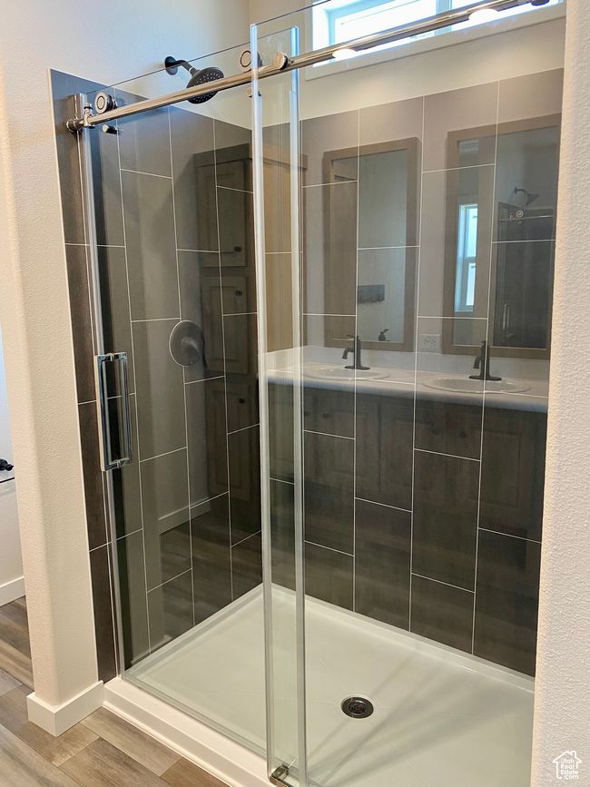 Bathroom featuring a shower stall, wood finished floors, and double vanity | Image 11