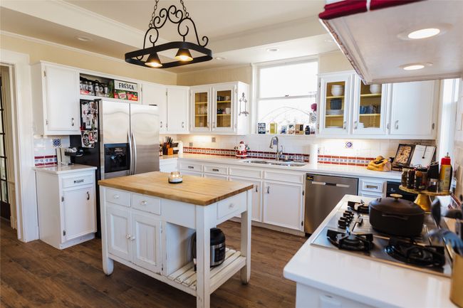 Kitchen featuring white cabinetry, appliances with stainless steel finishes, sink, hanging light fixtures, and a center island | Image 16