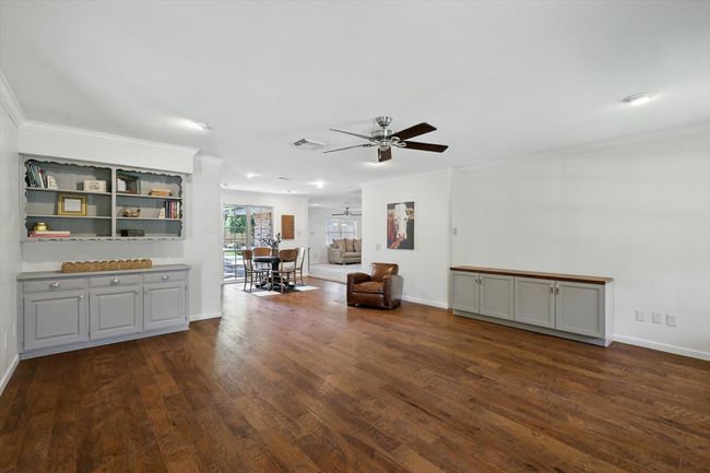 Living room with a ceiling fan, dark wood-type flooring, and ornamental molding | Image 7
