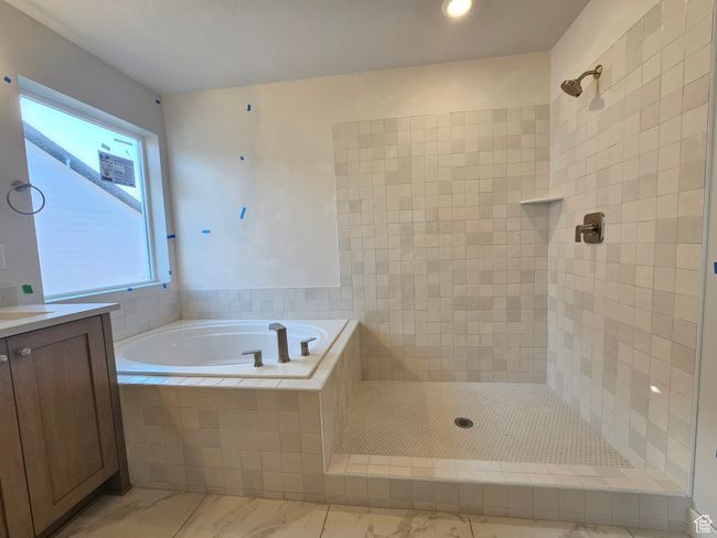 Bathroom with a garden tub, tiled shower, vanity, and marble finish flooring | Image 19