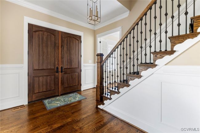 Entryway featuring a decorative wall, stairs, wainscoting, crown molding, and dark wood finished floors | Image 6