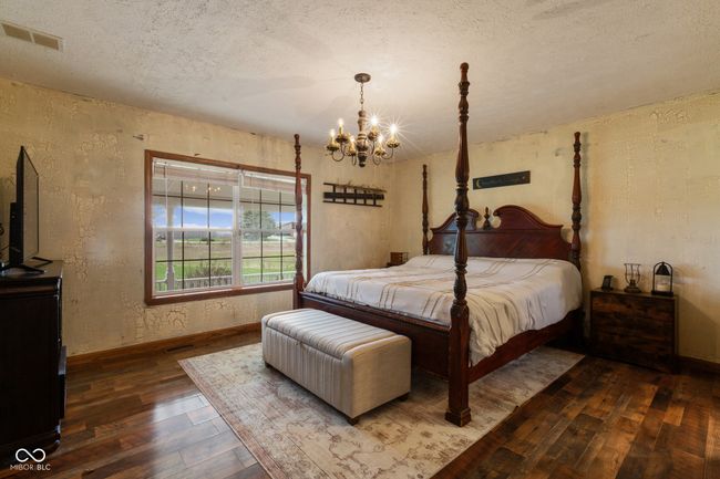 bedroom with a textured wall, wood-type flooring, visible vents, and an inviting chandelier | Image 33