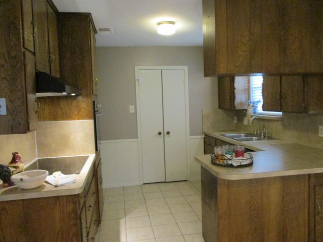 Kitchen featuring a sink, vent fan, light countertops, a peninsula, and light tile patterned flooring | Image 4