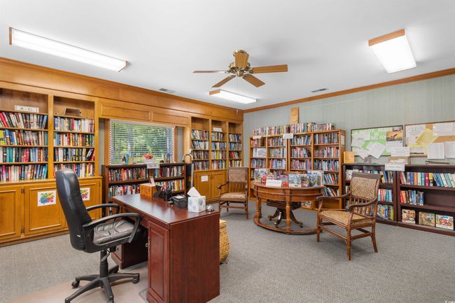 Office with wall of books, carpet floors, crown molding, ceiling fan, and wood walls | Image 34