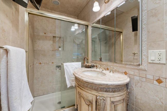 Full bathroom with vanity, tile walls, and a stall shower | Image 16