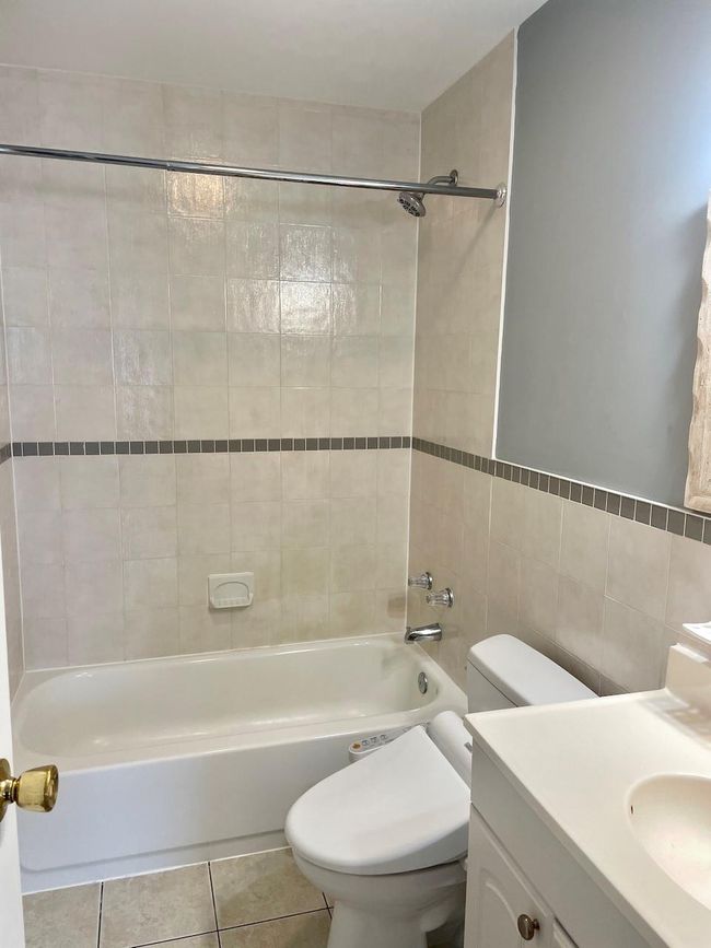 Bathroom featuring vanity, tile patterned floors, toilet, shower / bathing tub combination, and tile walls | Image 12