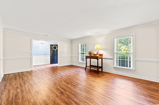 Empty room with a chandelier, wood finished floors, and crown molding | Image 9
