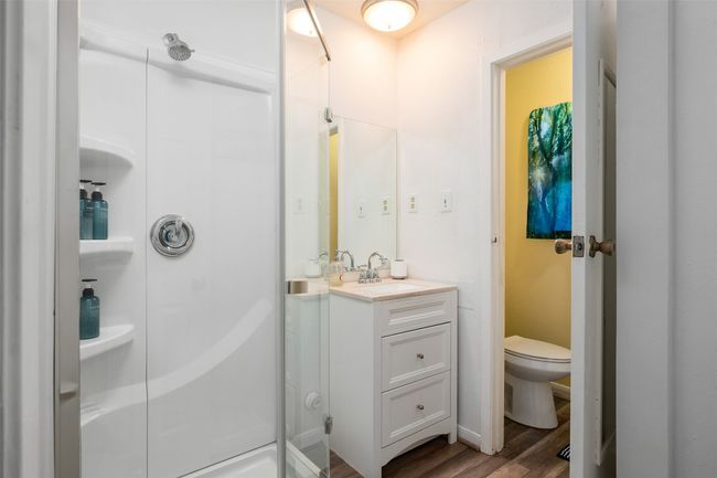 Bathroom with wood finished floors, toilet, vanity, and a shower stall | Image 10