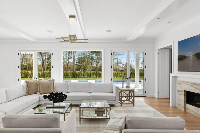 Living area featuring a premium fireplace, beamed ceiling, french doors, and recessed lighting | Image 8