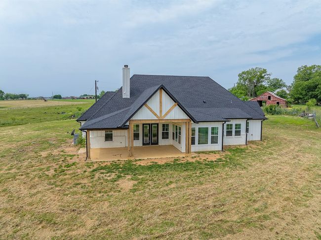 Back of property featuring a chimney, a patio, roof with shingles, and a yard | Image 36