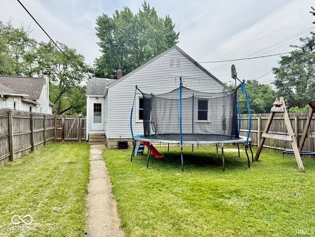 rear view of house featuring a trampoline and a fenced backyard | Image 4