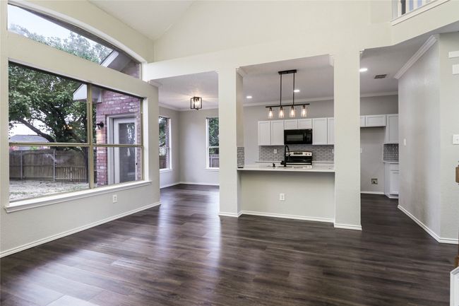 Kitchen featuring black microwave, electric range, plenty of natural light, light countertops, and high vaulted ceiling | Image 7