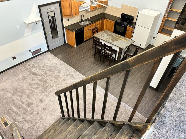Kitchen with ceiling fan, sink, dark wood-type flooring, decorative backsplash, and black appliances | Image 19