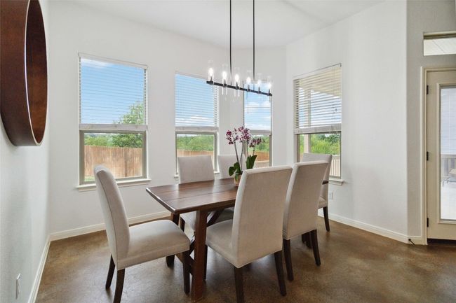 Dining room with concrete floors, plenty of natural light, a chandelier, and baseboards | Image 11