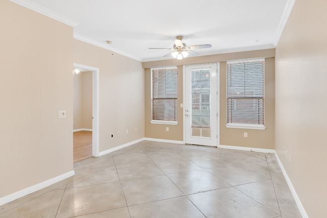 Living room with a new ceiling fan, crown molding, baseboards, and light tile patterned floors. All new paint and blinds. | Image 8