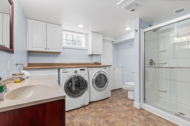 Large basement 3/4 bathroom also houses washer and dryer with folding counter and cabinetry | Image 29