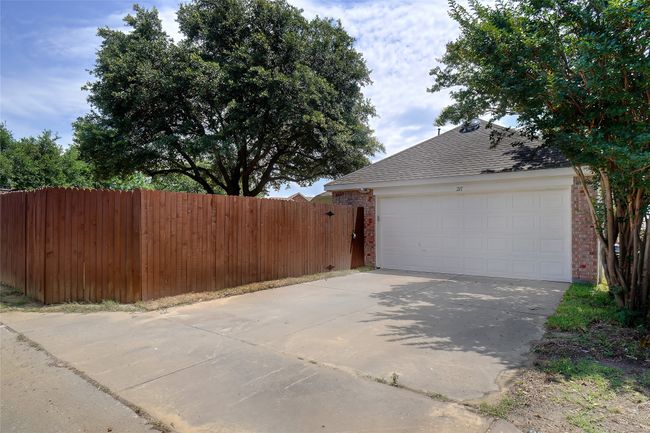 View of side of home with brick siding, driveway, a shingled roof, and an attached garage | Image 26