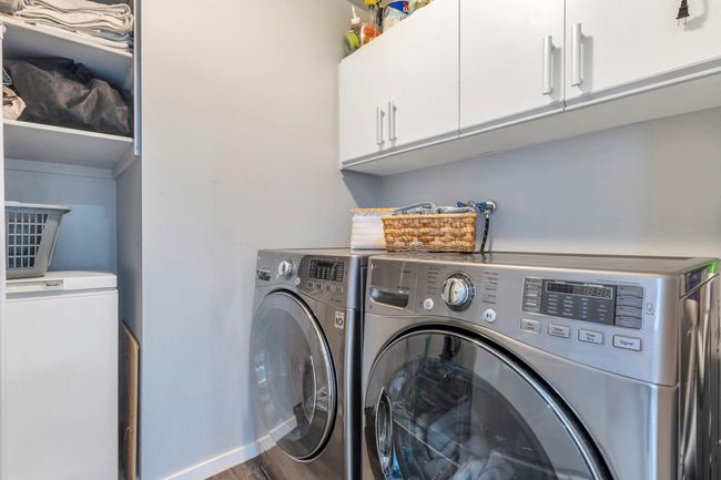 Laundry area featuring cabinet space, washer and dryer, baseboards, and wood finished floors | Image 16