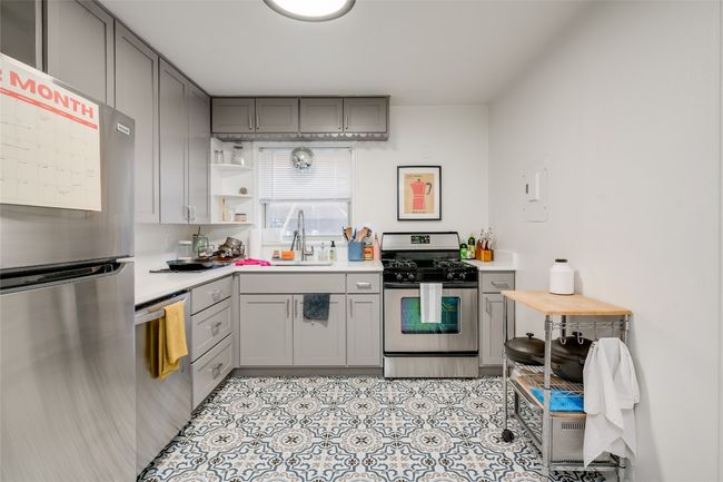 Kitchen featuring appliances with stainless steel finishes, gray cabinets, a sink, and light countertops | Image 16