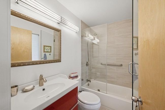 Bathroom featuring vanity, shower / bath combination with glass door, and toilet | Image 11