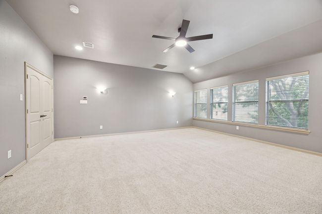 Spare room featuring a ceiling fan, carpet floors, lofted ceiling, a smoke detector, and baseboards | Image 29