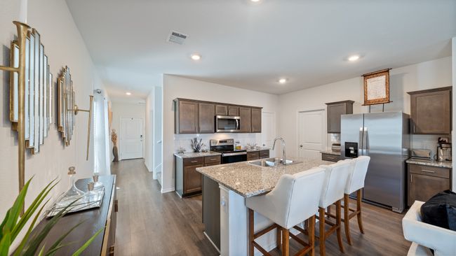 Kitchen with stainless steel appliances, tasteful backsplash, dark brown cabinets, a kitchen island with sink, and dark wood-type flooring | Image 5