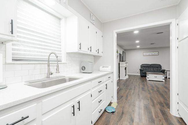 Kitchen featuring dark hardwood / wood-style flooring, backsplash, white cabinetry, and sink | Image 4
