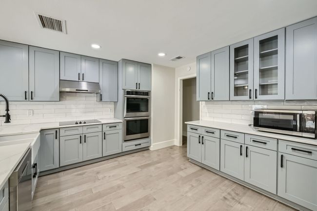 Kitchen featuring visible vents, stainless steel appliances, backsplash, and under cabinet range hood | Image 9