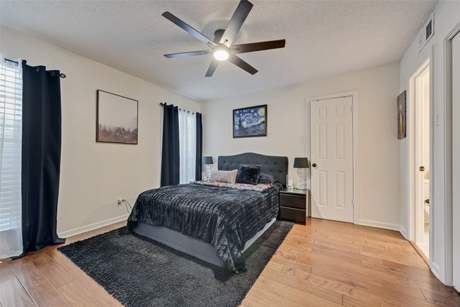 Bedroom featuring light wood-style flooring, a textured ceiling, multiple windows, and a ceiling fan | Image 11